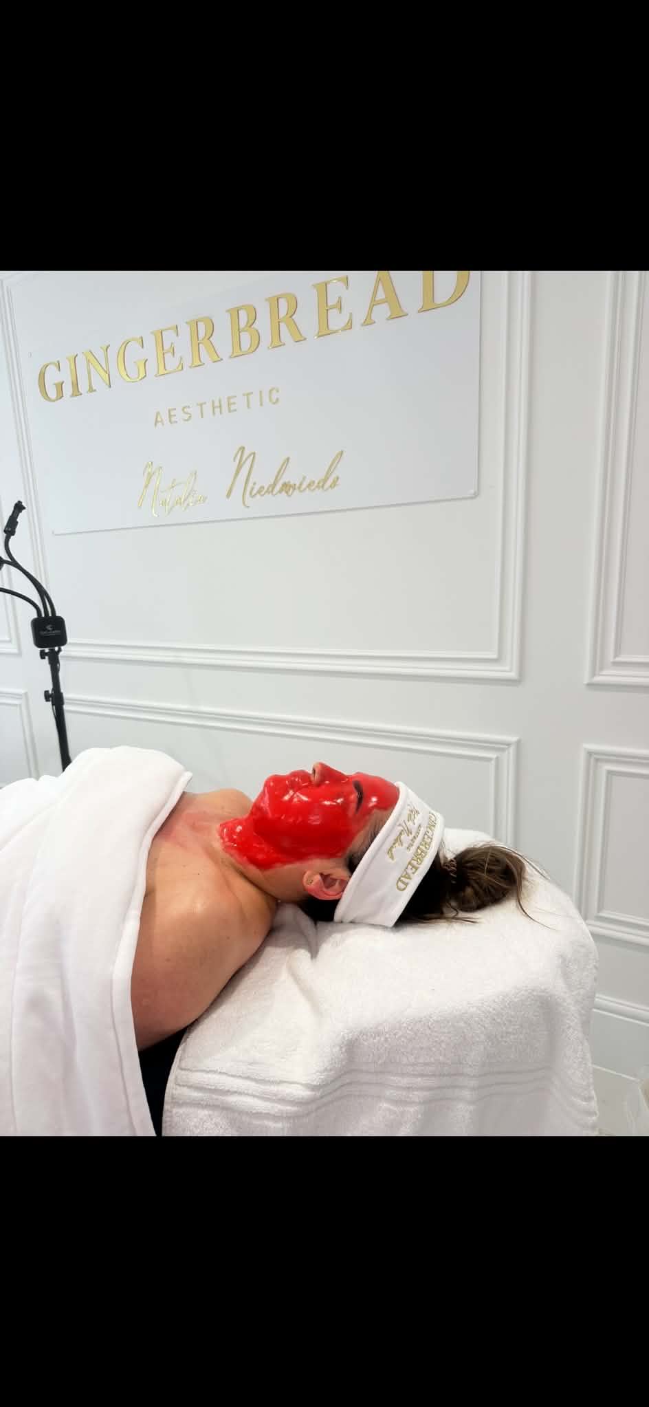 Client receiving a combined facial treatment at Gingerbread Aesthetic, Towcester, with the clinic's gold wall branding visible